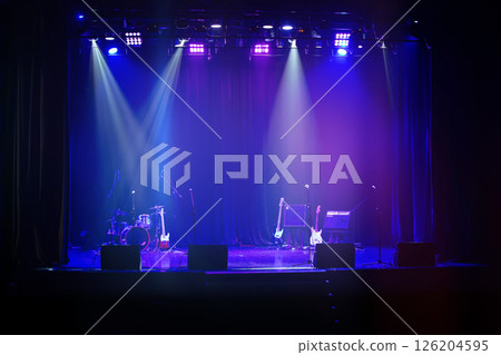 Dark background of the stage with musical instruments illuminated by a blue spotlight. Dark background of the stage with musical instruments illuminated by a blue spotlight. 126204595