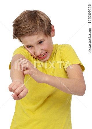 The boy in the yellow T-shirt is scratching his arm badly. The child has an allergy or dermatitis. He was bitten by insects. 126204666