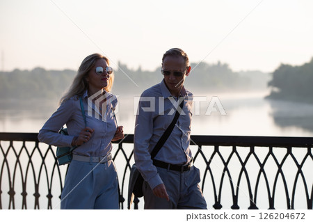 Adult men and a woman walking around the morning city. Tourists on a walk. 126204672
