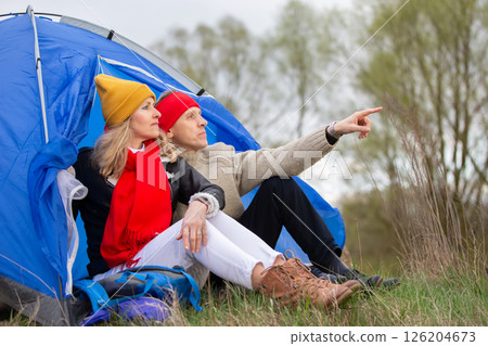 Active elderly Caucasian couple relaxing in a tent against the backdrop of autumn natural landscape. Man and woman tourists on a trip. 126204673