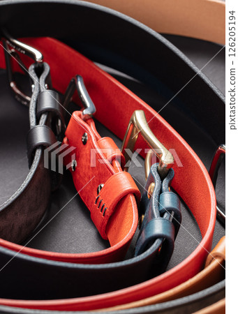 Various leather belts with metal buckles close-up on dark grey background. 126205194