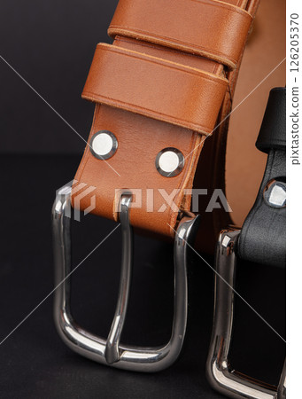 Leather belts with metal buckles on a gray background. 126205370