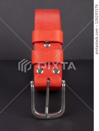 Red leather belt with metal buckles on a gray background. Red leather belt with metal buckles on a gray background. 126205576