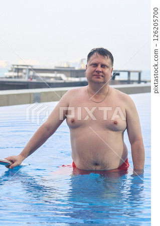 Joyful Plus-Size Man Enjoying a Refreshing Swim in a Pool on a Sunny Day 126205700