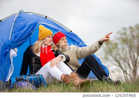 Active elderly Caucasian couple relaxing in a tent against the backdrop of autumn natural landscape. Man and woman tourists on a trip. Active elderly Caucasian couple relaxing in a tent against the backdrop of autumn natural landscape. Man and woman tourists on a trip. 126205988