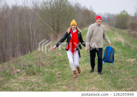 Active elderly Caucasian couple hiking with backpacks  enjoying their adventure. They sit with their backs to the camera. 126205999
