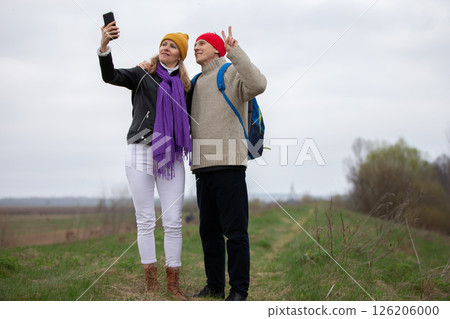 Active elderly Caucasian couple traveling with backpacks, enjoying their adventure. They take selfies. 126206000