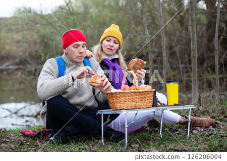 Man and woman elderly couple eating on tourist picnic in nature. Man and woman elderly couple eating on tourist picnic in nature. 126206004