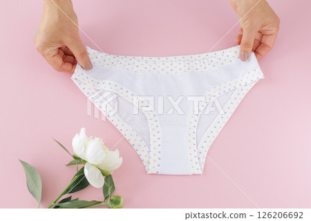 Women's hands with a white panties on the pink background. Women's hands with a white panties on the pink background. 126206692