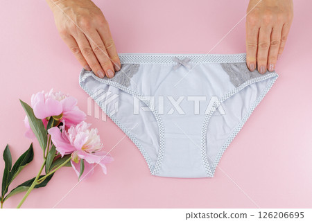 Women's hands with a gray panties on the pink background. 126206695