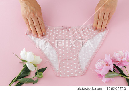 Women's hands with a pink panties on the pink background. Women's hands with a pink panties on the pink background. 126206720