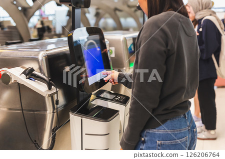 Woman using service machine for self check in at airport. 126206764