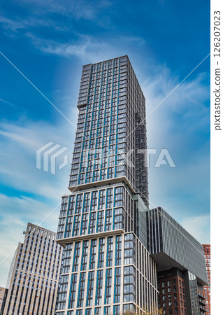Modern High Rise Skyscraper Towering Against a Clear Blue Sky in Urban Cityscape 126207023
