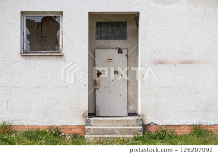 Abandoned building detail with damaged doors and broken glass on window 126207092