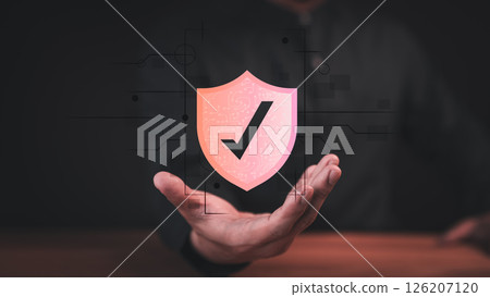 Male hand showing a glowing shield with the checkmark icon, symbolizing security, protection, and trust. Concept of emphasizes digital safety, authentication, and confidence in modern technology. Male hand showing a glowing shield with the checkmark icon, symbolizing security, protection, and trust. Concept of emphasizes digital safety, authentication, and confidence in modern technology. 126207120