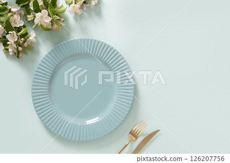 Elegance empty blue plate and spring blossom flowers on blue background. Mock up. Table setting concept. Kitchen decoration, food styling, or dining presentations. Copy space. View from above. Elegance empty blue plate and spring blossom flowers on blue background. Mock up. Table setting concept. Kitchen decoration, food styling, or dining presentations. Copy space. View from above. 126207756