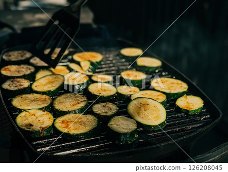 Grilled zucchini slices cooking on a hot grill pan with golden sear marks 126208045