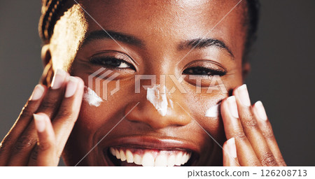 Happy, black woman and portrait with face cream in studio for skincare on a gray background. Closeup, female person or model with smile in satisfaction for lotion, moisturizer or facial treatment Happy, black woman and portrait with face cream in studio for skincare on a gray background. Closeup, female person or model with smile in satisfaction for lotion, moisturizer or facial treatment 126208713