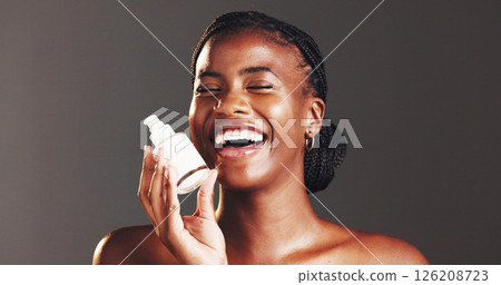 Black woman, skincare and cream in portrait, studio and bottle for dermatology by background. African person, girl and product with lotion for beauty, glow or cosmetics with laughing in Nigeria Black woman, skincare and cream in portrait, studio and bottle for dermatology by background. African person, girl and product with lotion for beauty, glow or cosmetics with laughing in Nigeria 126208723