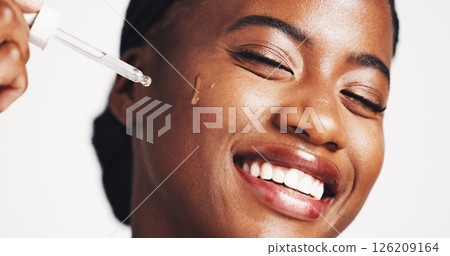 Skincare, serum and woman with product, smile and moisturizing of face with liquid, hydration and studio. White background, happy and black person with cosmetics for treatment, glow and smooth skin 126209164