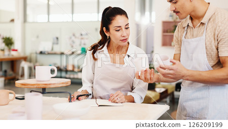 Pottery class, question and instructor in ceramic workshop with help, explain and clay product. Advice, man and woman in studio with support, feedback and sculpture design mold in small business 126209199