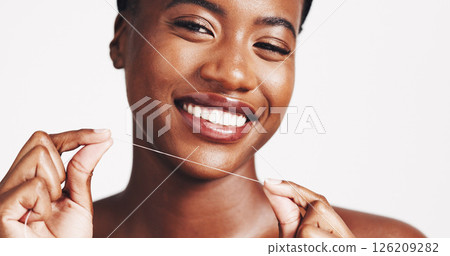 Portrait, black woman and smile with floss in studio of teeth whitening, dental hygiene and oral care. Happy, person and string with veneers, fresh breathe and clean results on white background Portrait, black woman and smile with floss in studio of teeth whitening, dental hygiene and oral care. Happy, person and string with veneers, fresh breathe and clean results on white background 126209282