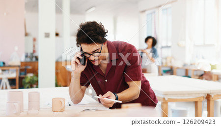 Phone call, pottery and man in workshop with tablet pen for inventory, schedule or order clay supply. Ceramic art, person and talking with technology for chat, client follow up and creative craft 126209423