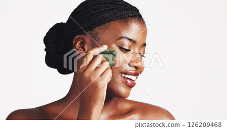 Cosmetics, skincare and black woman with gua sha in studio for lymphatic drainage, natural beauty or self care. Dermatology, girl and smile with jade stone for radiant skin on white background mockup 126209468