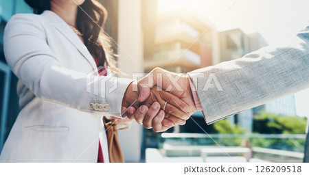 Business people, city and handshake with partnership for B2B deal, agreement or meeting. Closeup, employees or colleagues shaking hands with lens flare for greeting or introduction in an urban town 126209518