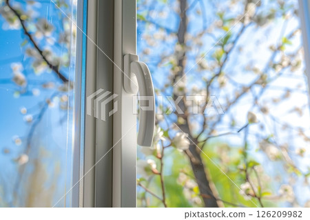 New plastic PVC window with white metal frame installed at modern house, view of blurred green trees, blue sky. Advertising. Typical installation of insulated glazing windows with uPVC window frames. 126209982