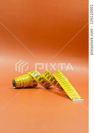 From above of tailor measuring sewing tape on orange background in bright light From above of tailor measuring sewing tape on orange background in bright light 126210001