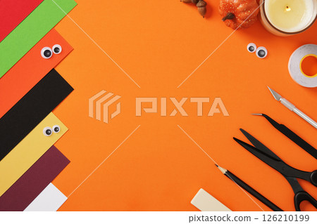 Supplies for paper crafts in Halloween colors. Pencil, eraser, knife, scissors, tape and colored pieces of paper. Copyspace. Supplies for paper crafts in Halloween colors. Pencil, eraser, knife, scissors, tape and colored pieces of paper. Copyspace. 126210199