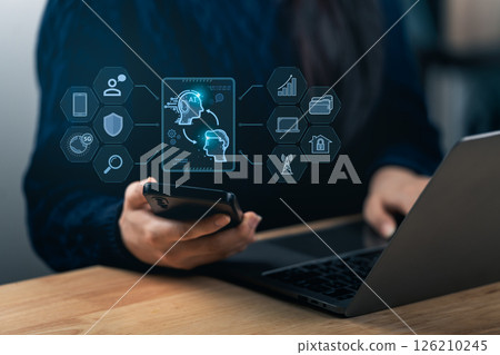 A person engages with a smartphone and a laptop, displaying AI technology and data visualization. The scene represents modern workspace innovation and digital communication. A person engages with a smartphone and a laptop, displaying AI technology and data visualization. The scene represents modern workspace innovation and digital communication. 126210245