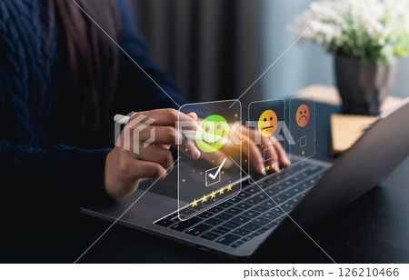 Close-up hand woman interacts with a laptop to express feedback using emotion icons and star ratings, reflecting the importance of customer satisfaction digital workplace. 126210466