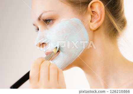 Girl apply green mud mask to face 126210866