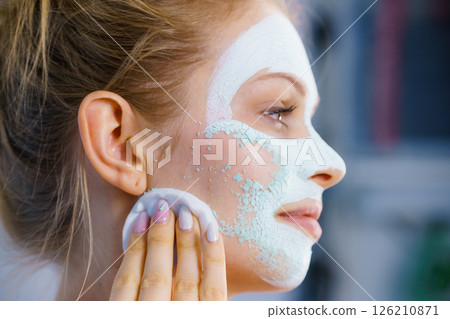 Girl removes dry white mud mask Girl removes dry white mud mask 126210871