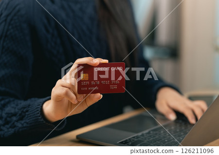 Person Holding Credit Card in Front of Laptop, Online Payment, Digital Transactions, Home Office Setup, E-commerce Shopping Concept 126211096