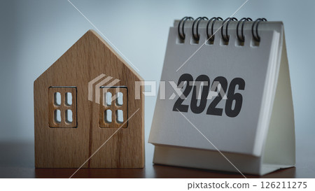 Wooden house model and a calendar with the date of the new year 2026. Wooden house model and a calendar with the date of the new year 2026. 126211275