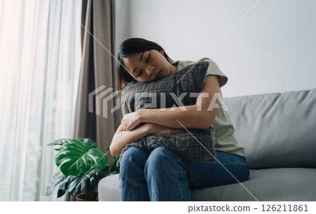 Unhappy lonely depressed woman is sitting on the couch. She looks sad and tired. Unhappy lonely depressed woman is sitting on the couch. She looks sad and tired. 126211861