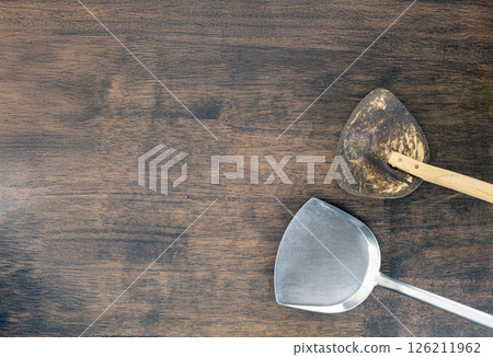 Metal and wooden spatulas rest on rustic wooden table, showcasing blend of materials and textures. contrast between shiny metal and worn wood adds character to kitchen tools 126211962