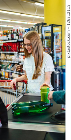 Smiling woman at checkout in vibrant grocery store environment Smiling woman at checkout in vibrant grocery store environment 126212115