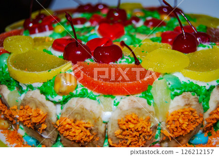 Sponge cake with fruits. Creatively decorated sponge cake with banana, orange, lemon, marmalade wedges and pickled cherries. Sponge cake with fruits. Creatively decorated sponge cake with banana, orange, lemon, marmalade wedges and pickled cherries. 126212157