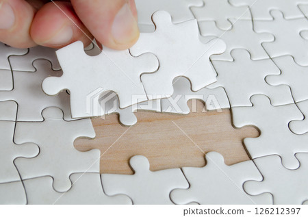 Hand placing missing jigsaw puzzle pieces. Solution concept. Hand placing missing jigsaw puzzle pieces. Solution concept. 126212397