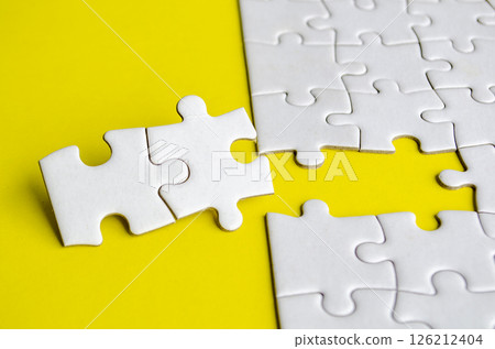 Close up view of missing white jigsaw puzzles, symbolizing partnership and unity on yellow background. 126212404