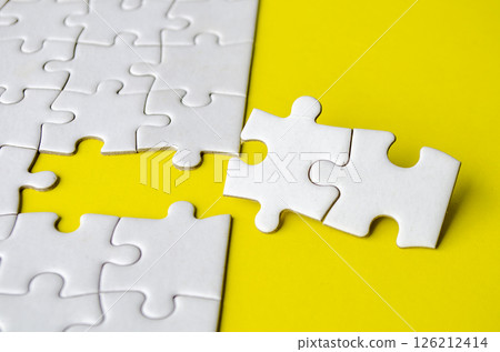 Close up view of missing white jigsaw puzzles, symbol of partnership and unity on yellow background. 126212414