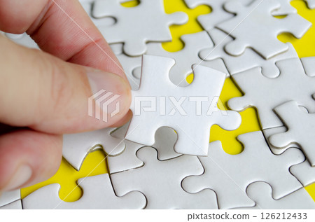 Close up of hand place missing jigsaw puzzle representing problem solving skill. Close up of hand place missing jigsaw puzzle representing problem solving skill. 126212433