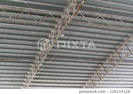 Industrial ceiling with exposed beams and structural elements in modern building, showing metal trusses and corrugated panels in spacious interior 126214128