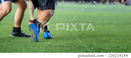Soccer players in action during game on grass field focusing on their legs and ball, showing movement and competition in sports setting 126214144