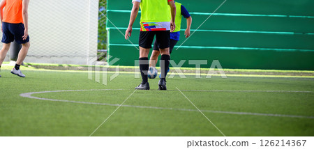 Soccer players in action during game on grass field focusing on their legs and ball, showing movement and teamwork in sports setting 126214367