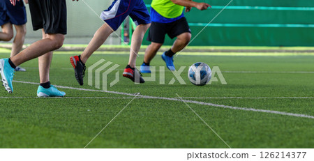 Soccer players in action during game on grass field focusing on their legs and ball, showing dynamic movement and competitive energy 126214377